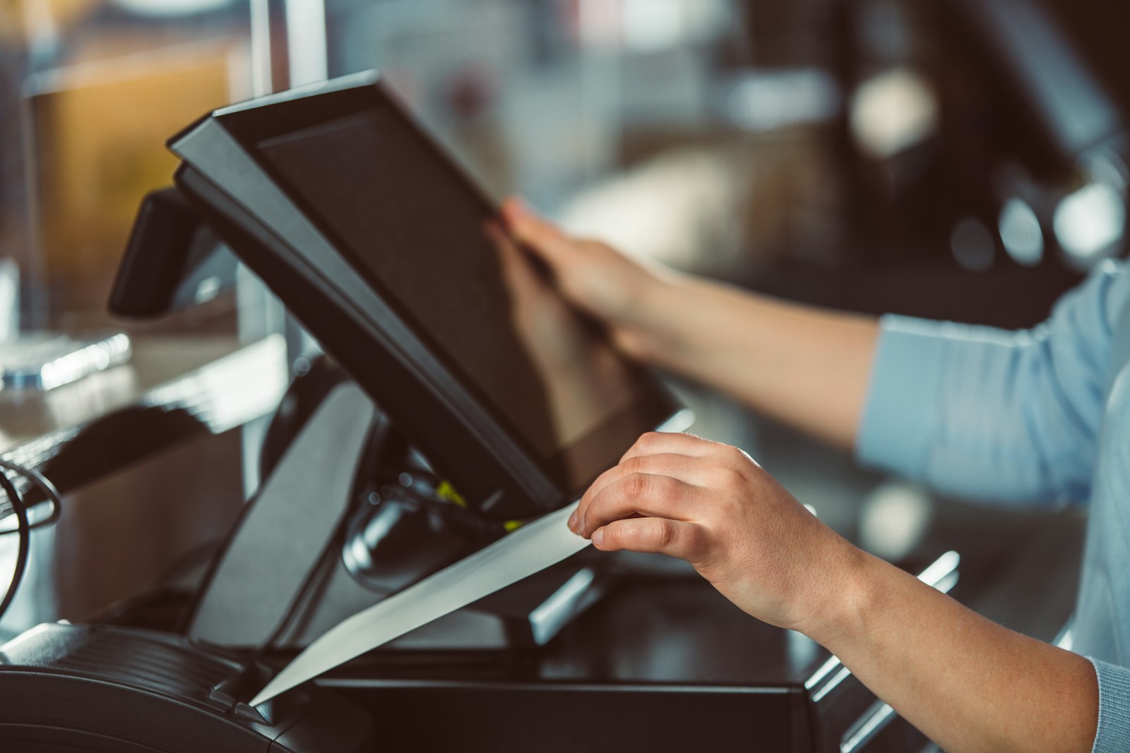 Illustrative photo of a staff member operating a point-of-sale terminal, representing the operator login step