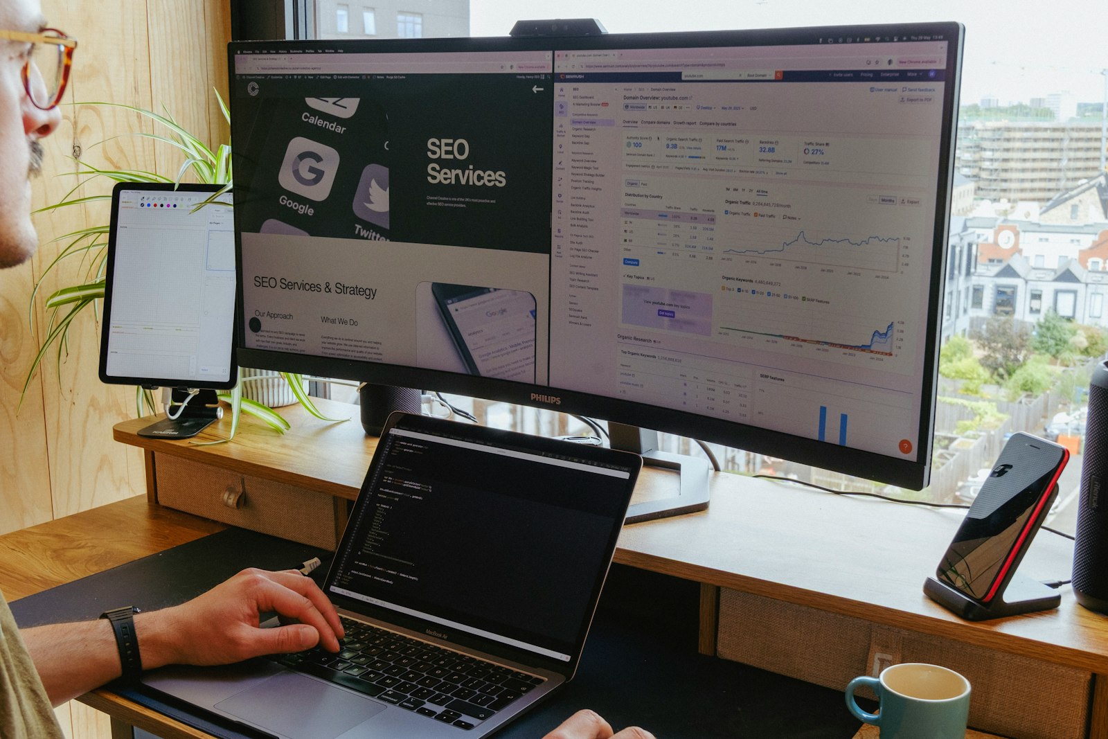 Multi-monitor web development workspace showing a website and an SEO dashboard